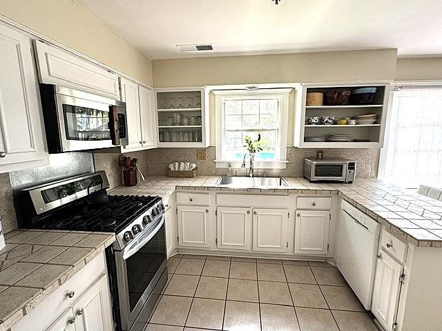 1897 Corbin Road Germantown, TN 38139 - Photo 5 of 22 U-shaped kitchen featuring white cabinetry, tile countertops, and a tile backsplash