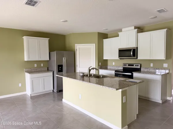 a kitchen with stainless steel appliances a stove a sink a refrigerator a microwave a sink and cabinets