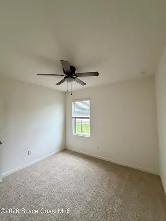an empty room with a window and a ceiling fan