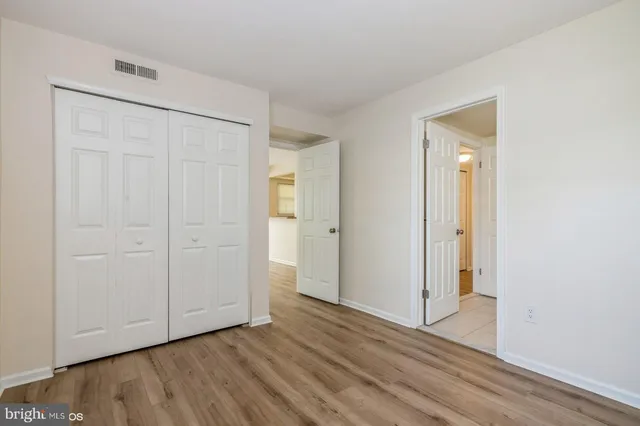 a view of an empty room with wooden floor and closet