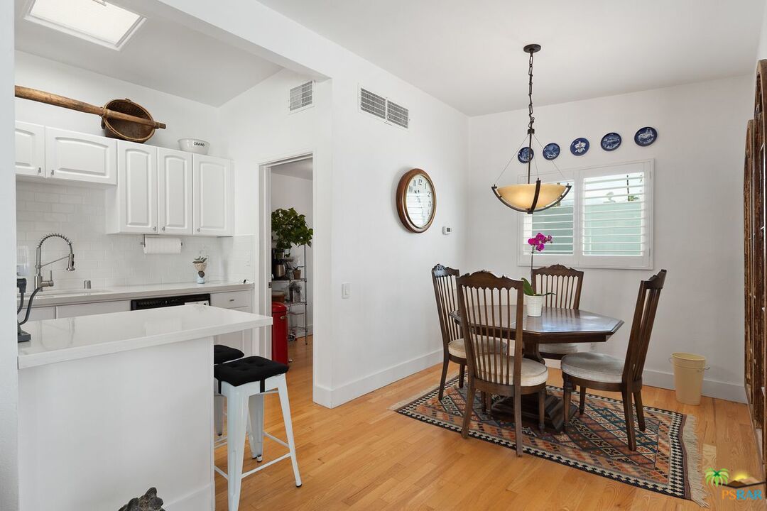 73501 Silver Moon Trail Palm Desert, CA 92260 - Photo 15 of 38 a view of a dining room and kitchen with furniture wooden floor and a clock