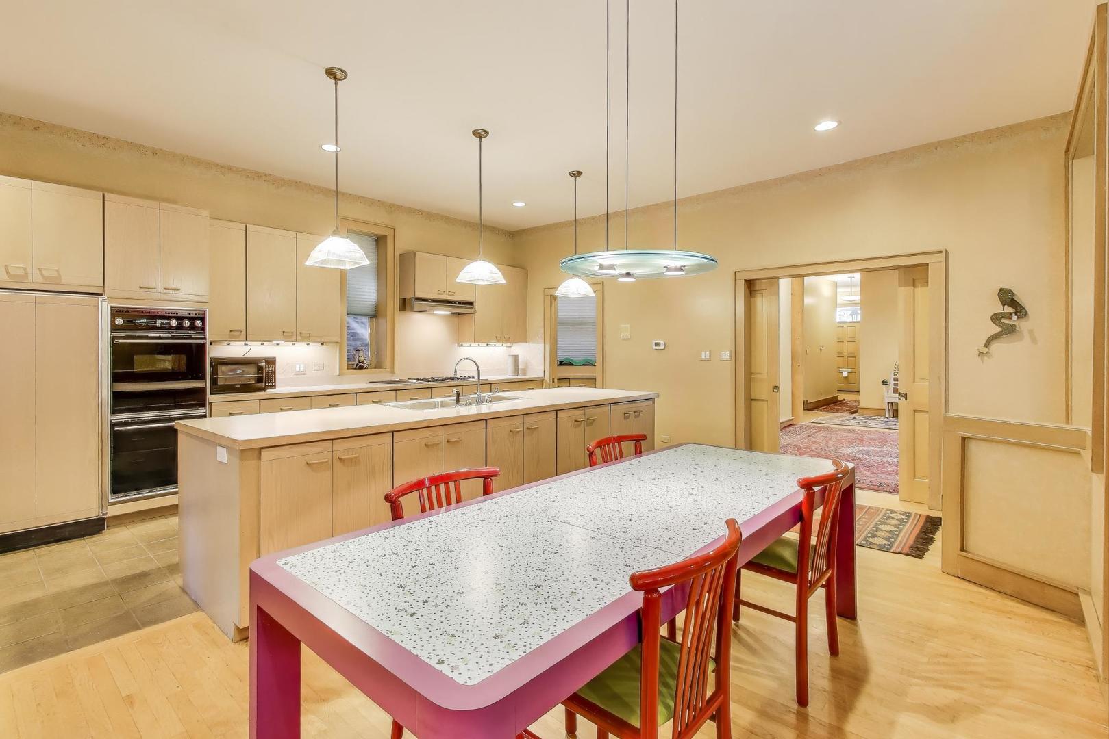 907-909 West Webster Avenue Chicago, IL 60614 - Photo 13 of 71 a kitchen with stainless steel appliances kitchen island granite countertop a table chairs and a refrigerator