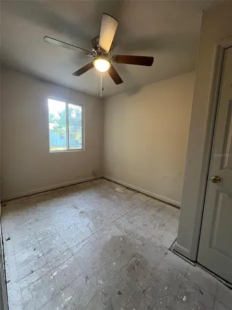 en empty room with windows and ceiling fan