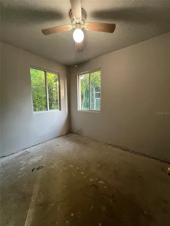 a view of an empty room with window and chandelier fan