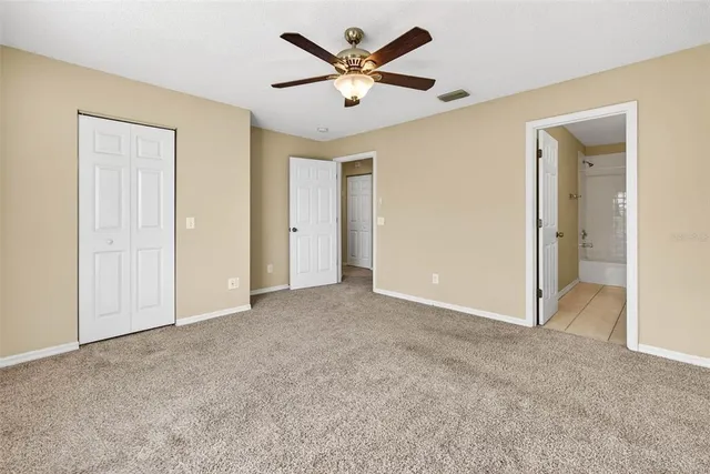 an empty room with closet and a ceiling fan