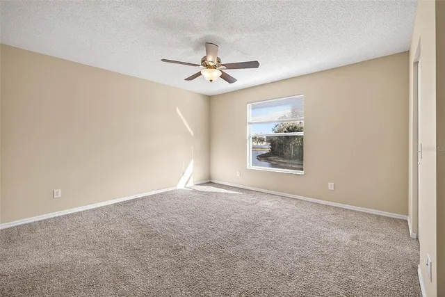 an empty room with windows and fan