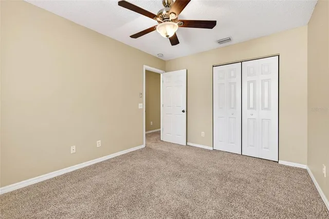 an empty room with closet and a ceiling fan