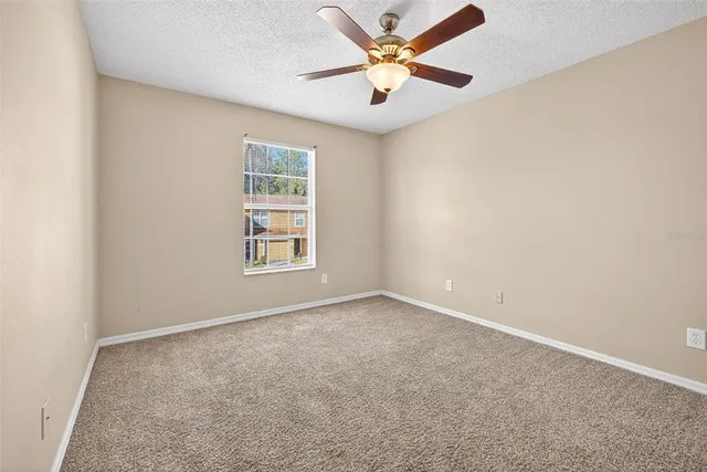 an empty room with a window and a fan