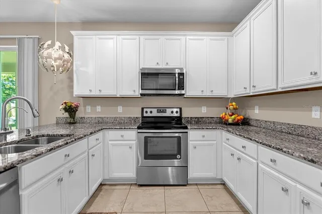 a kitchen with granite countertop white cabinets white stainless steel appliances and a sink