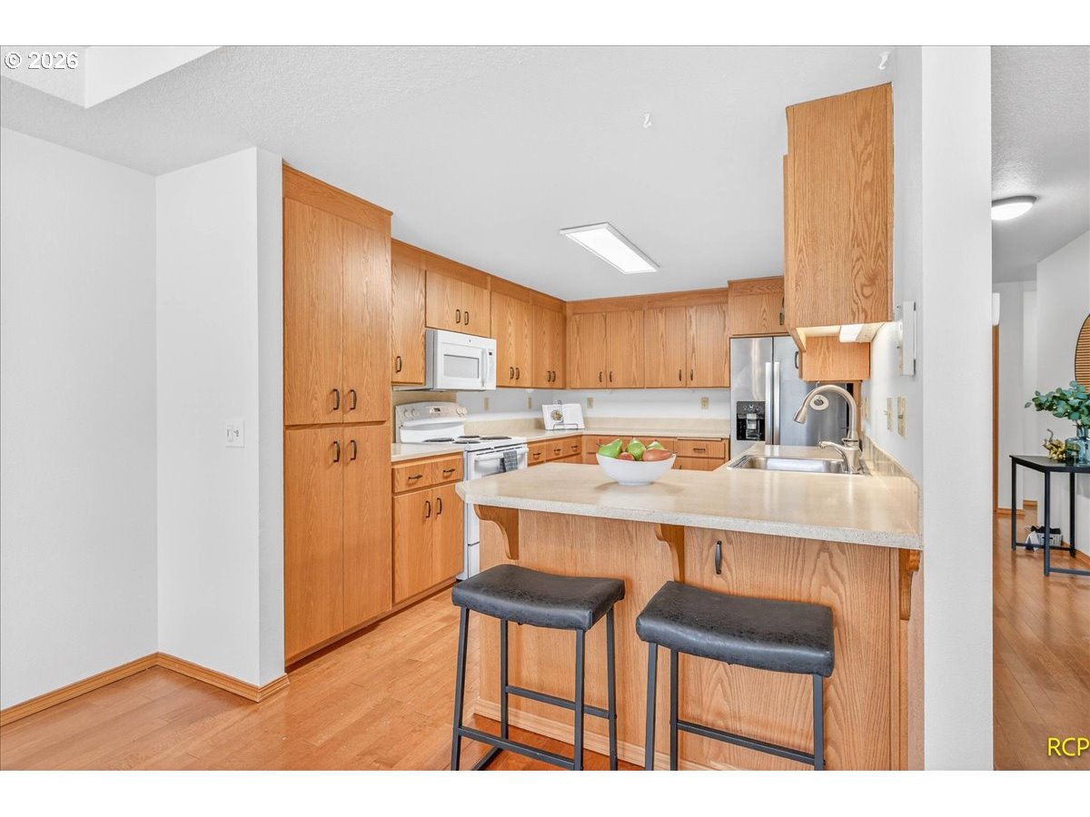 16444 Southwest 130th Terrace, Unit 121 Portland, OR 97224 - Photo 17 of 40 a kitchen with kitchen island a stove a sink refrigerator and cabinets