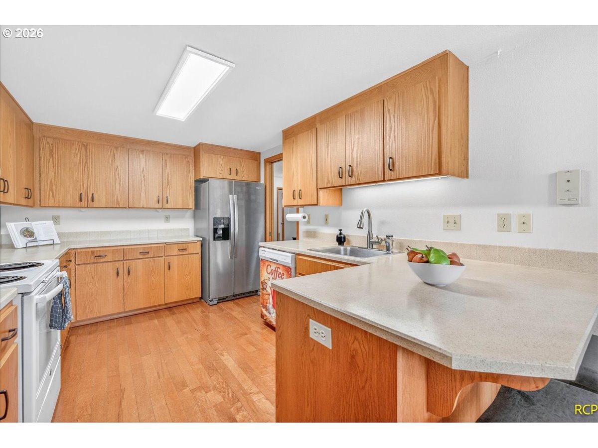 16444 Southwest 130th Terrace, Unit 121 Portland, OR 97224 - Photo 19 of 40 a kitchen with stainless steel appliances a sink a stove a refrigerator a center island and cabinets