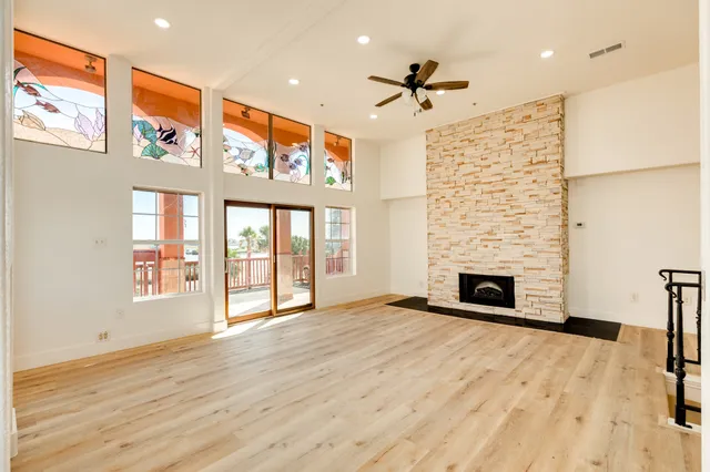 a view of an empty room with wooden floor and a fireplace