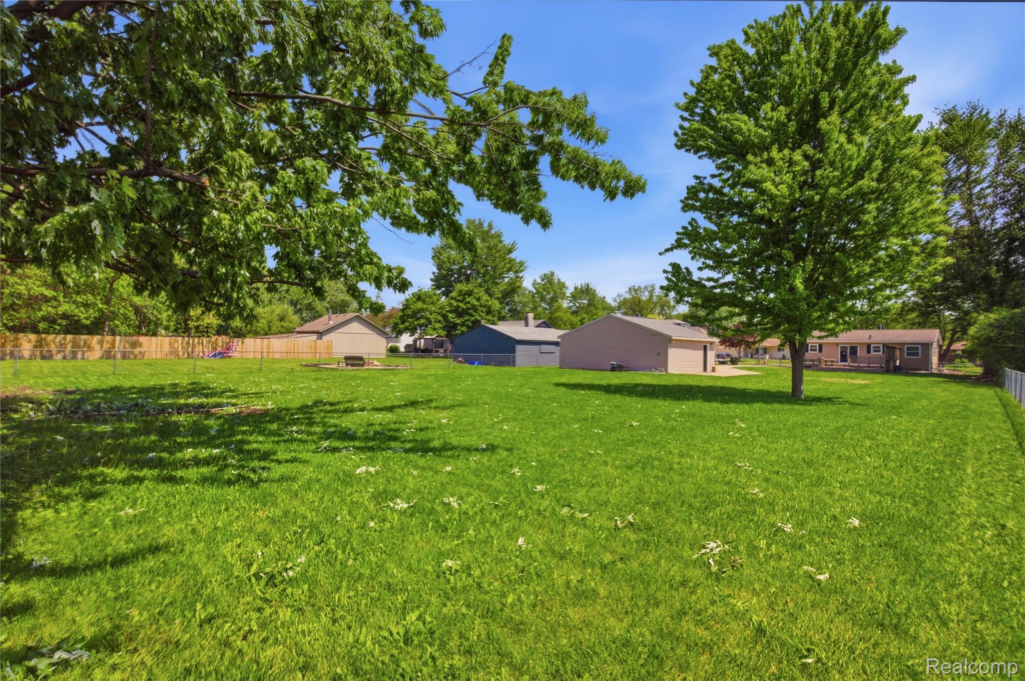 37257 Dundee Street Sterling Heights, MI 48310 - Photo 38 of 47 Expansive backyard featuring a lush lawn, mature trees, and partial perimeter fencing