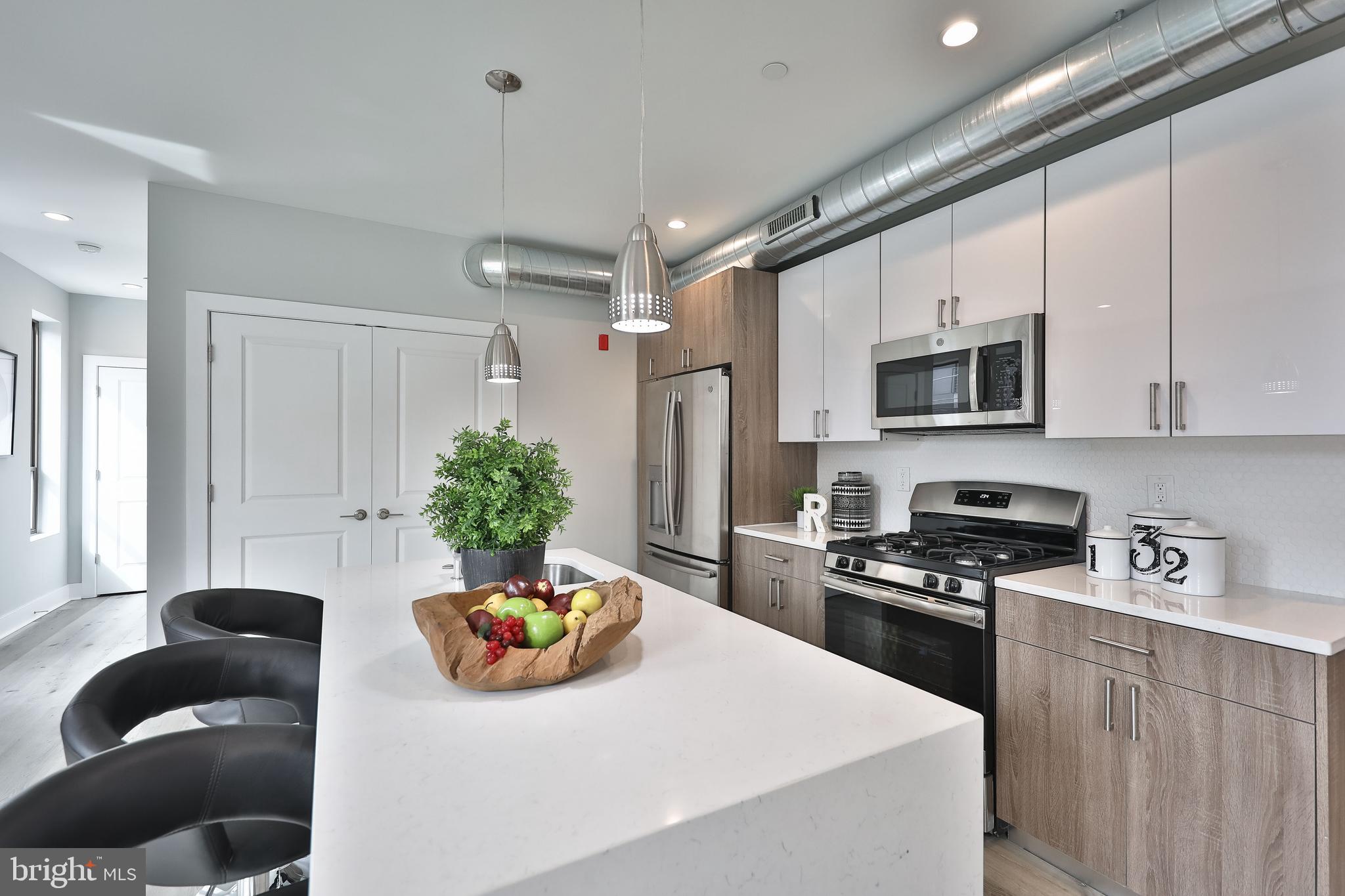 1540-42 Ridge Avenue, Unit 2S Philadelphia, PA 19130 - Photo 6 of 20 a kitchen with stainless steel appliances a stove a sink a microwave a refrigerator and cabinets