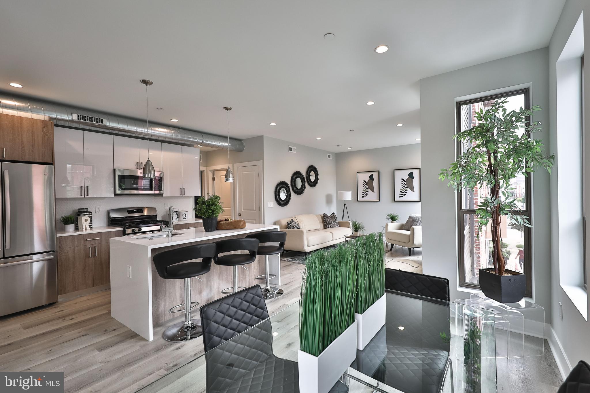 1540-42 Ridge Avenue, Unit 2S Philadelphia, PA 19130 - Photo 10 of 20 a kitchen with stainless steel appliances granite countertop a refrigerator a sink dishwasher a dining table and chairs with wooden floor