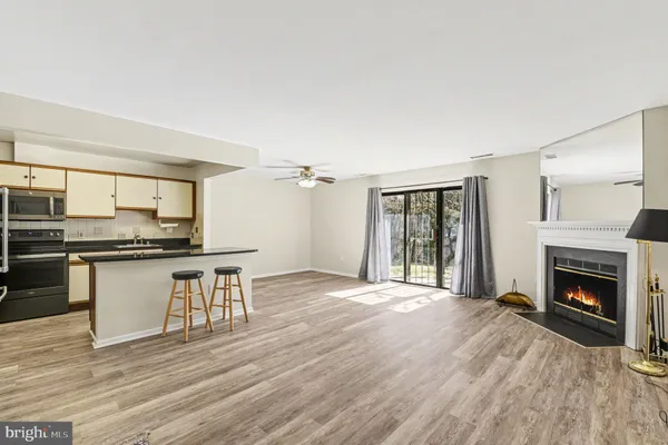 a open kitchen with granite countertop a stove top oven a sink dishwasher and a fireplace with wooden floor