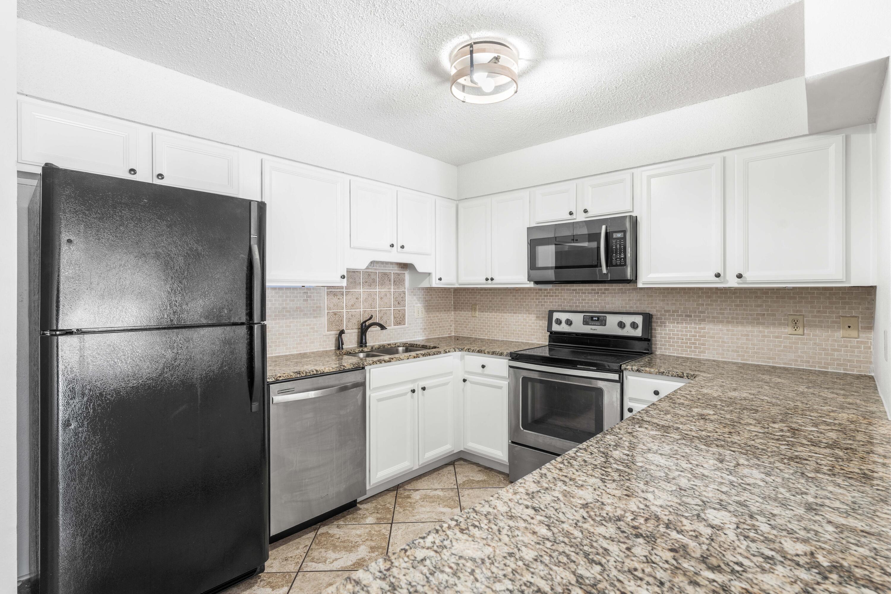 3654 East County Highway 30A, Unit 8B Santa Rosa Beach, FL 32459 - Photo 8 of 42 a kitchen with stainless steel appliances granite countertop a refrigerator a stove a sink and a microwave
