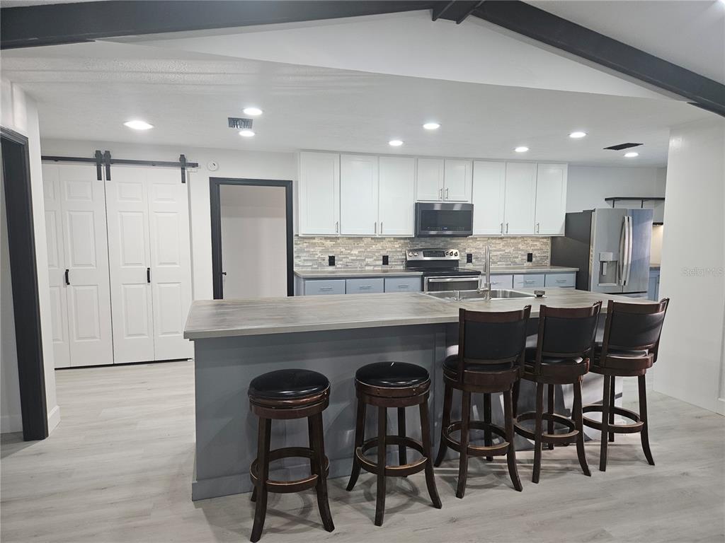 985 Southeast 56th Court Ocala, FL 34480 - Photo 6 of 36 a kitchen with kitchen island granite countertop wooden cabinets and chairs