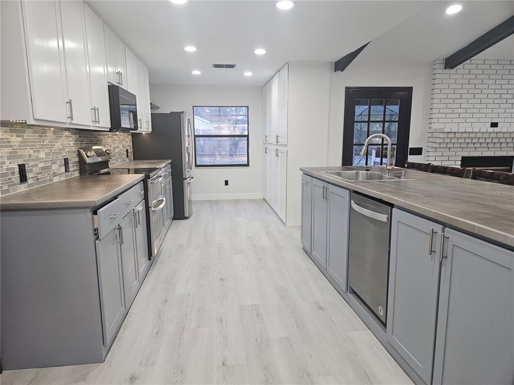 985 Southeast 56th Court Ocala, FL 34480 - Photo 7 of 36 a kitchen with stainless steel appliances granite countertop a sink stove and cabinets