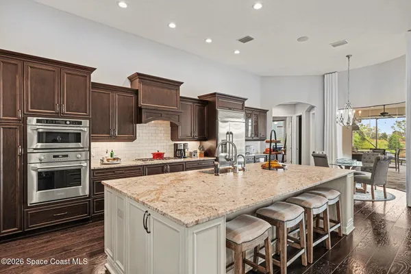 a kitchen with stainless steel appliances granite countertop a kitchen island a stove and a sink