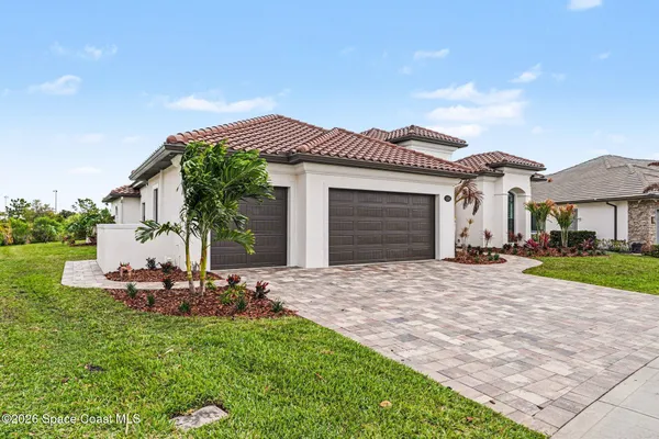 a front view of a house with a garden and chairs