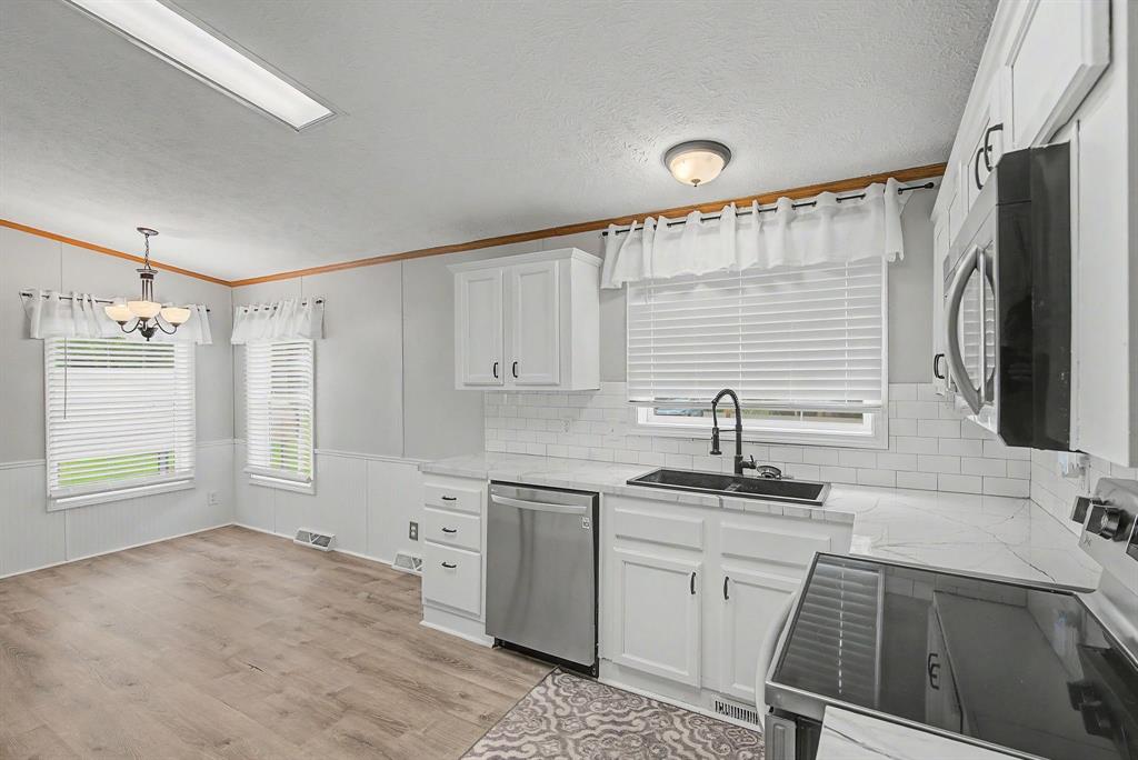 1202 Princeton Road Princeton, LA 71067 - Photo 8 of 19 Kitchen featuring white cabinetry, subway tile backsplash, stainless steel appliances, wood-finish flooring, and a dining area with a chandelier