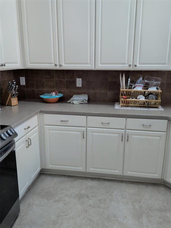 1848 Sandpiper Lane Carrollton, TX 75007 - Photo 4 of 8 Kitchen with electric range, white cabinets, and backsplash