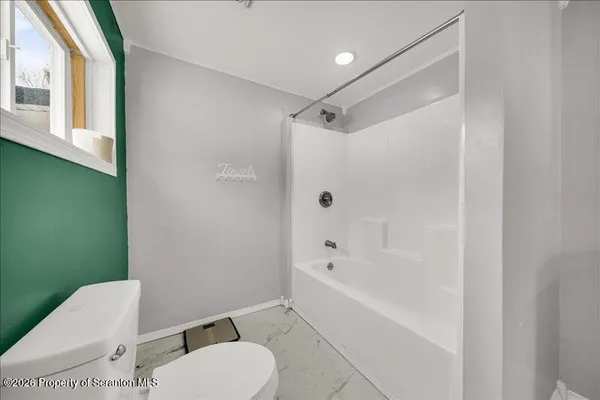 a white toilet sitting next to a bath tub shower