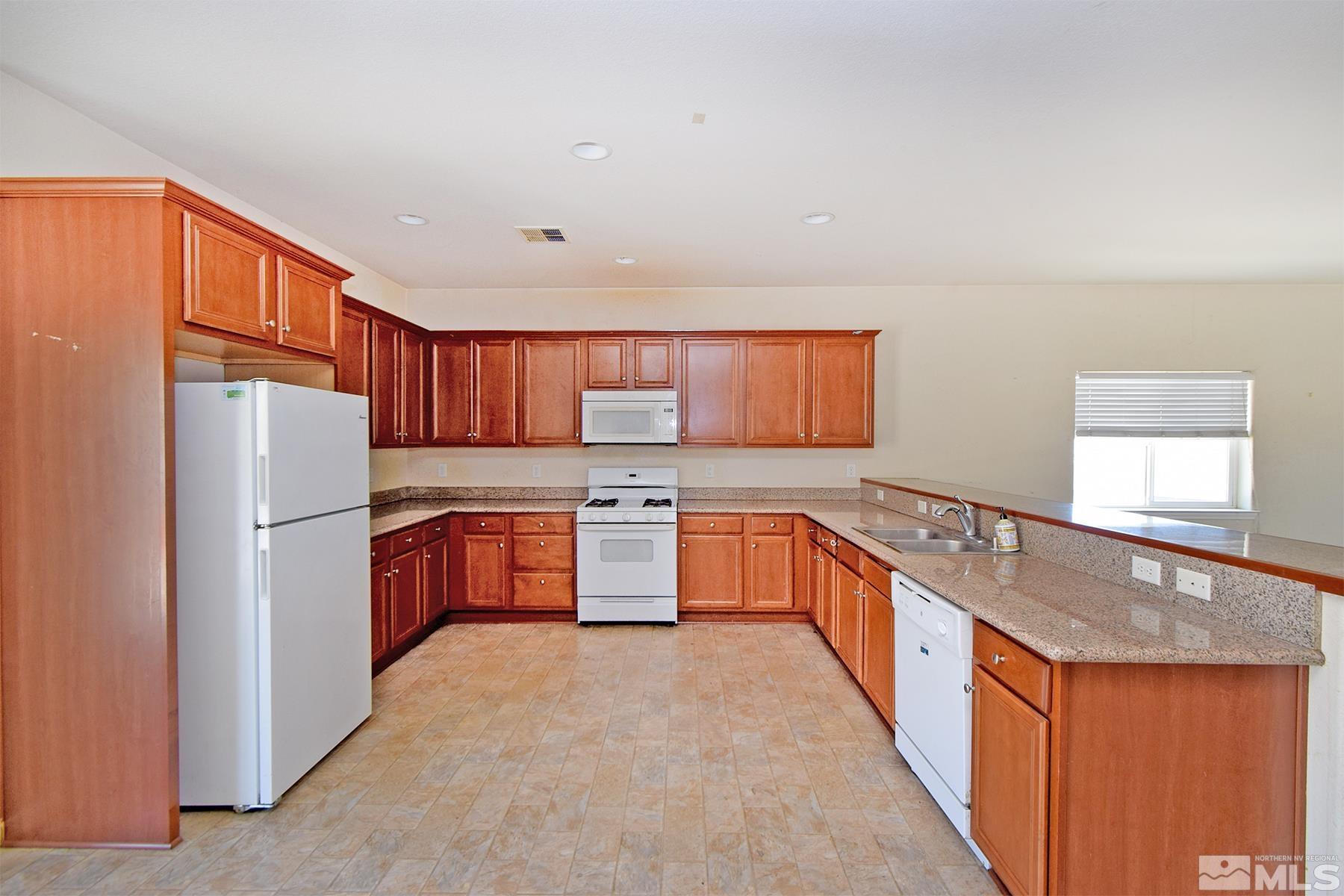 a kitchen with stainless steel appliances granite countertop a refrigerator a sink a stove with wooden cabinets