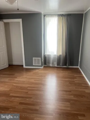 an empty room with wooden floor and windows with curtains