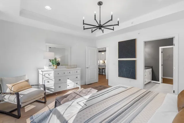 a bedroom with a bed chandelier and a window