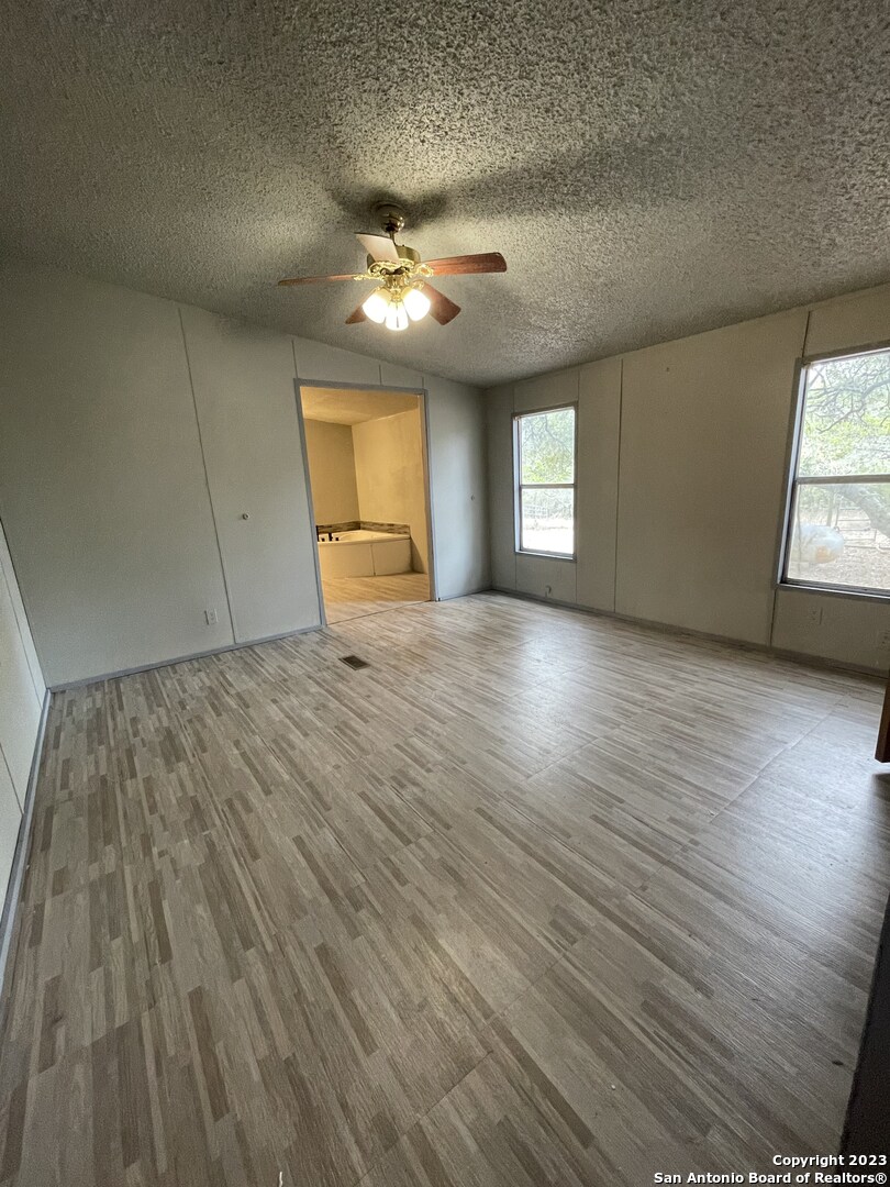 125 Pecan Drive Spring Branch, TX 78070 - Photo 9 of 12 an empty room with wooden floor and windows