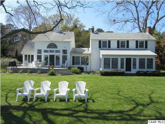 a front view of a house with swimming pool and chairs