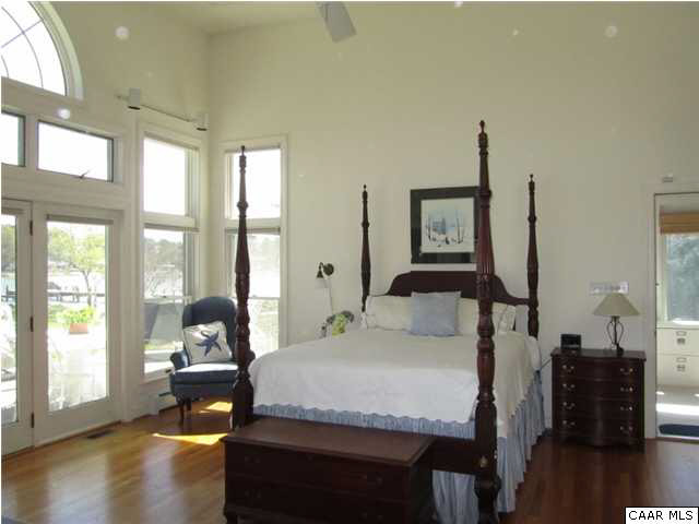 664 Horseshoe Bend Road Deltaville, VA 23043 - Photo 7 of 12 a bedroom with a bed and large windows