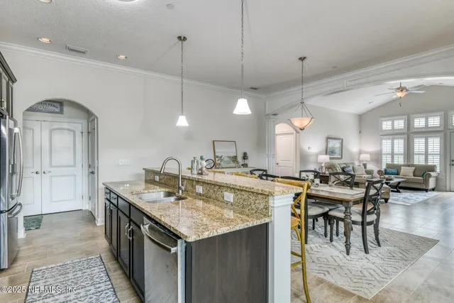 a kitchen with stainless steel appliances kitchen island granite countertop a table chairs in it and wooden floors