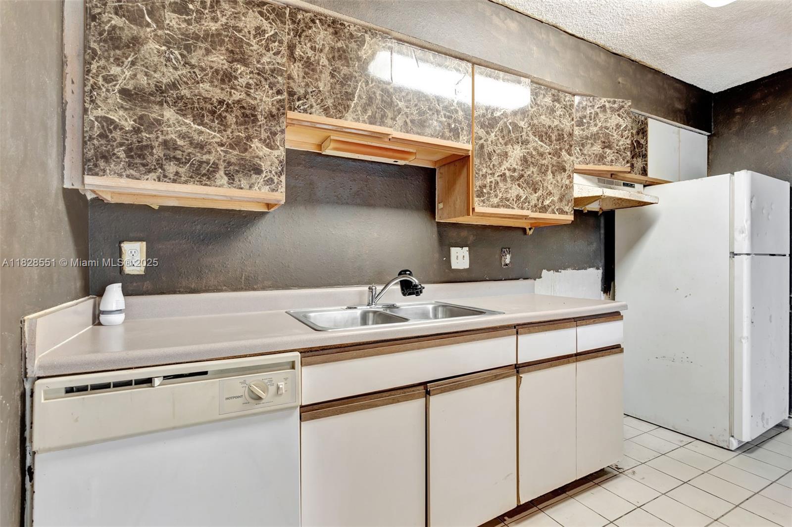 4055 West McNab Road, Unit H103 Pompano Beach, FL 33069 - Photo 6 of 21 a kitchen with stainless steel appliances a sink and a refrigerator