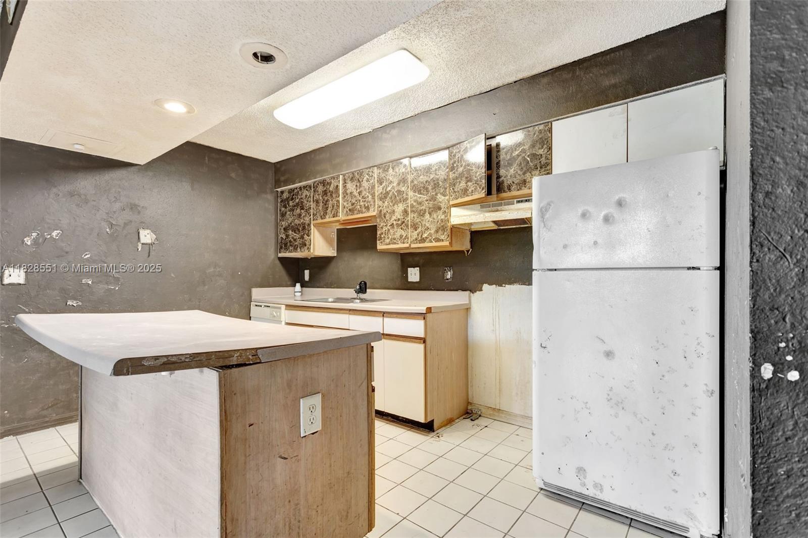 4055 West McNab Road, Unit H103 Pompano Beach, FL 33069 - Photo 7 of 21 a kitchen with a sink a refrigerator and cabinets