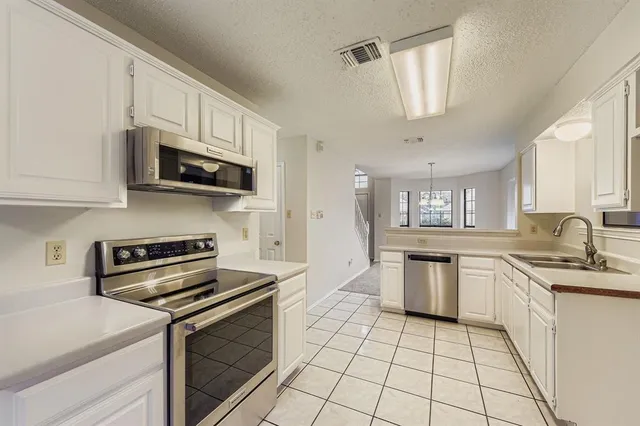 a kitchen with stainless steel appliances granite countertop a sink a stove a microwave and cabinets