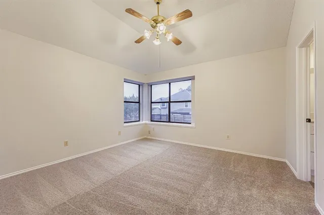 an empty room with a ceiling fan and a window