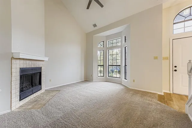 an empty room with windows and fireplace