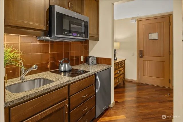 a dining hall with stainless steel appliances granite countertop a sink table and chairs