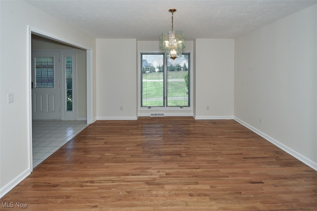 30776 Cedar Road Cleveland, OH 44124 - Photo 16 of 41 Unfurnished dining area featuring a chandelier, a textured ceiling, and wood finished floors