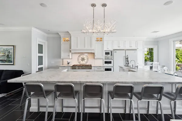 a kitchen with stainless steel appliances granite countertop a dining table chairs and a refrigerator