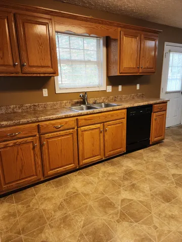 a kitchen with granite countertop a sink window and cabinets