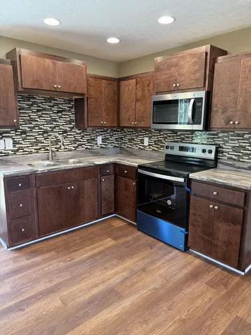 a kitchen with stainless steel appliances granite countertop a stove a sink and a microwave