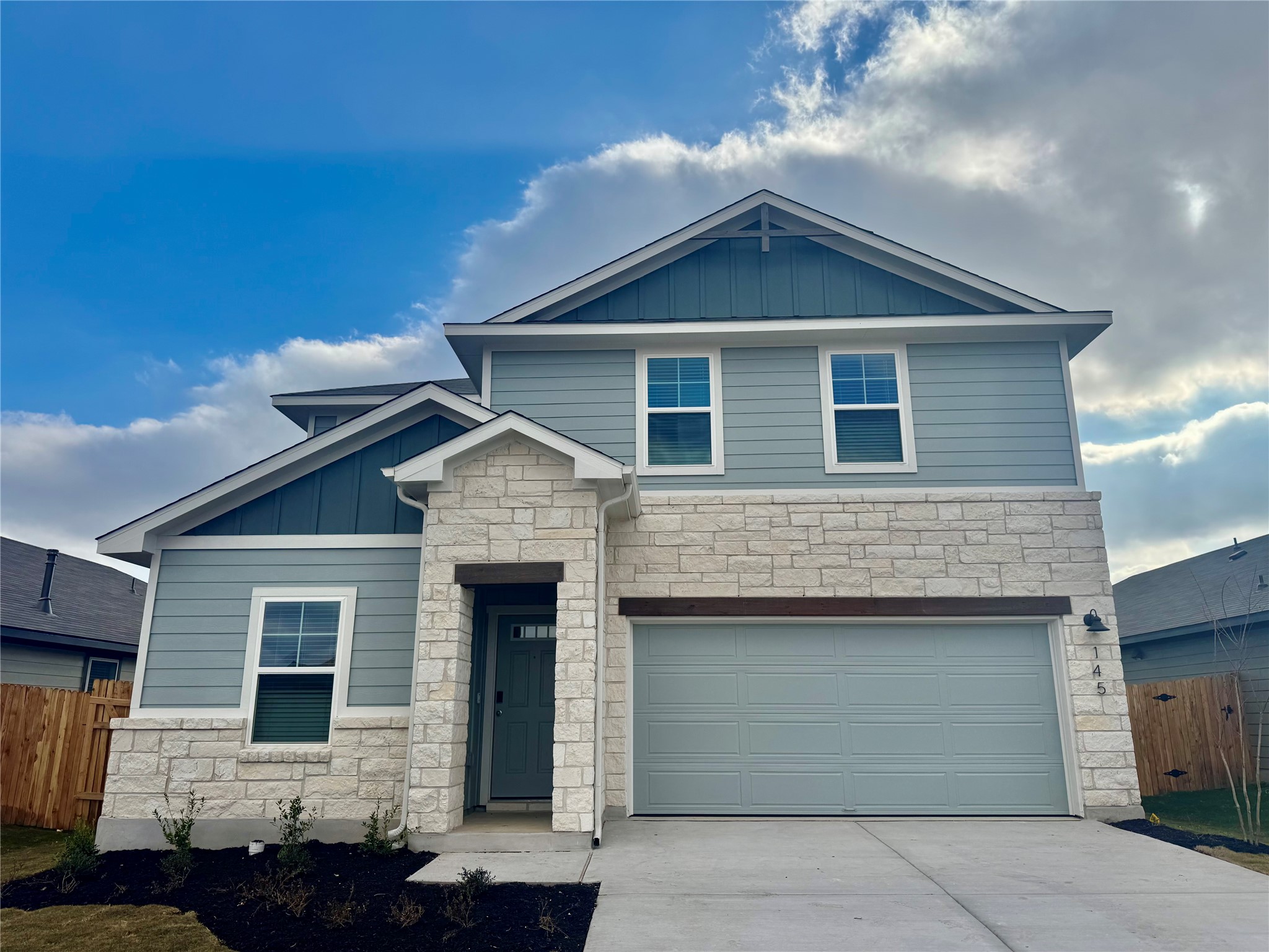 Craftsman house with board and batten siding, stone siding, and driveway