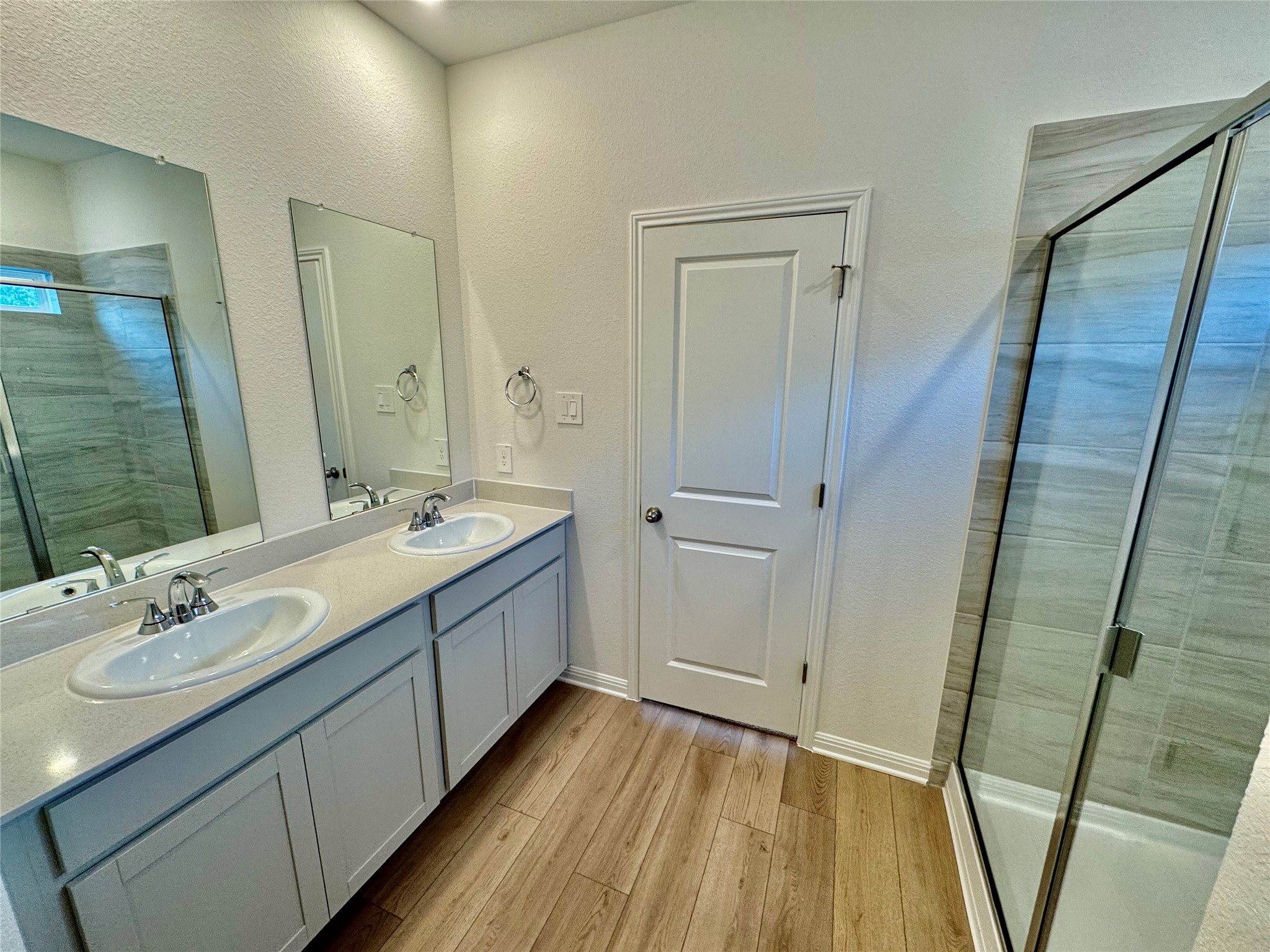 145 Boondoggle Ridge Cedar Creek, TX 78612 - Photo 4 of 21 Full bath featuring a stall shower, double vanity, light wood-type flooring, and a textured wall