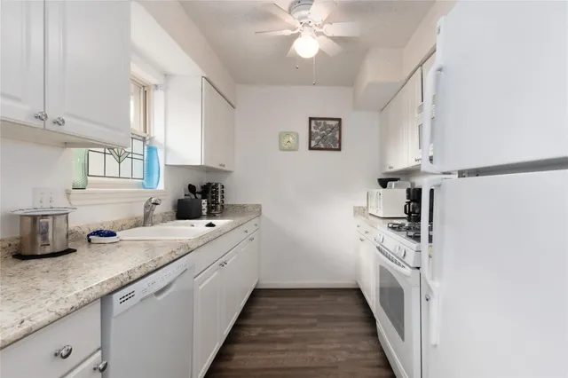 a kitchen with a sink dishwasher and white cabinets with wooden floor