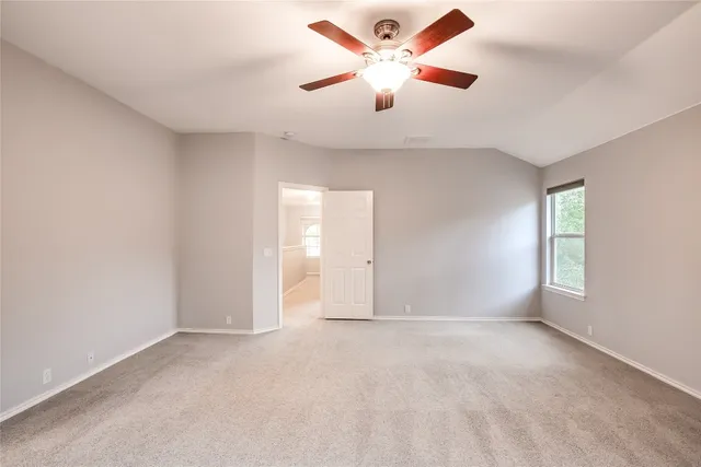 an empty room with chandelier fan and windows