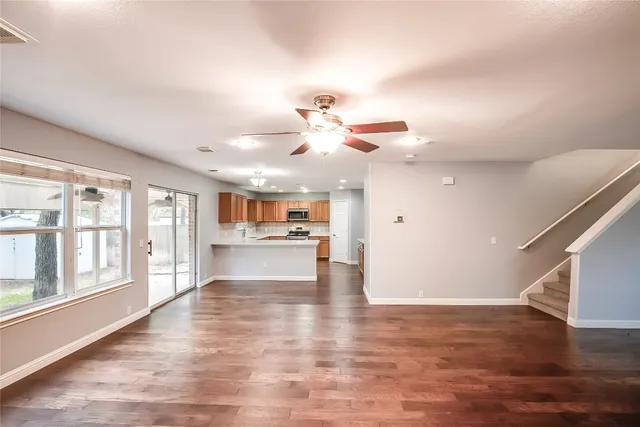 a view of an empty room with a window and wooden floor